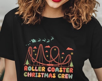 May include: Black t-shirt with a colorful graphic of a roller coaster with Santa and reindeer flying above it. The text "Roller Coaster Christmas Crew" is below the roller coaster.