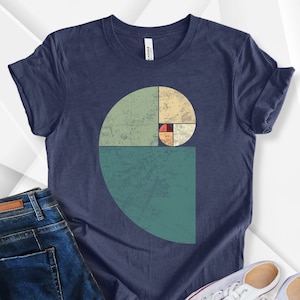 Może przedstawiać: Koszulka w kolorze granatowym z grafiką w stylu vintage przedstawiającą spiralę złotego podziału w kolorze zielonym, żółtym i czerwonym.
