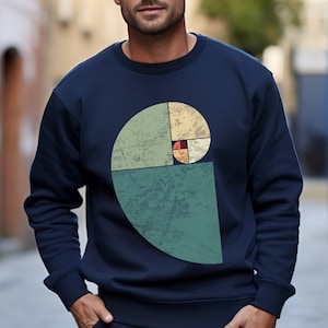 以下が含まれることがあります： 緑、黄色、赤、オレンジの色合いでフィボナッチ螺旋のヴィンテージスタイルのグラフィックが施されたネイビーブルーのスウェットシャツです。