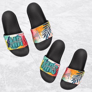 May include: A pair of black slide sandals with a colorful tropical print and the text "Mr. Smith est. 2025" on one sandal and "Mrs. Smith est. 2025" on the other.