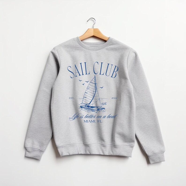May include: Grey sweatshirt with a blue graphic of a sailboat and the text "SAIL CLUB EST. 2004 Life is better on a boat MIAMI, FL"