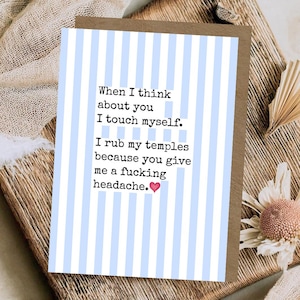 May include: A greeting card with a light blue and white vertical striped pattern. The text reads: When I think about you I touch myself. I rub my temples because you give me a fucking headache. A small pink heart icon follows the text.