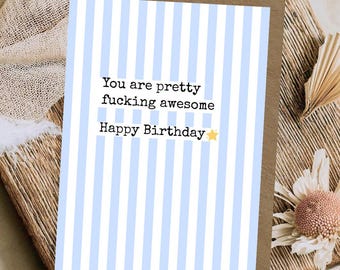 May include: A rectangular greeting card featuring a vertical light blue and white striped pattern. The text reads, "You are pretty fucking awesome Happy Birthday" with a small yellow star icon next to the final word on the card.