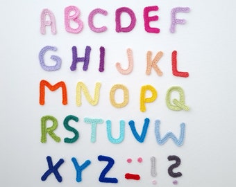May include: A colourful alphabet made of crocheted yarn. The letters are arranged in alphabetical order and are in various colours, including pink, purple, orange, yellow, green, blue, and red.