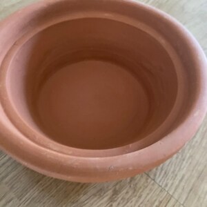May include: A terracotta pot with a smooth, rounded interior. The pot is made of natural clay and has a rustic, earthy appearance.