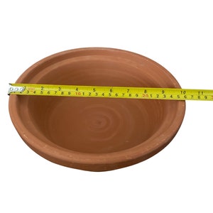 May include: A terracotta bowl with a diameter of 10 inches. The bowl is made of unglazed clay and has a natural brown color.