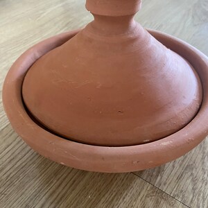 May include: A terracotta tagine pot with a lid. The pot is a traditional Moroccan cooking vessel.
