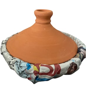 May include: A terracotta tagine cooking pot with a lid, wrapped in newspaper.