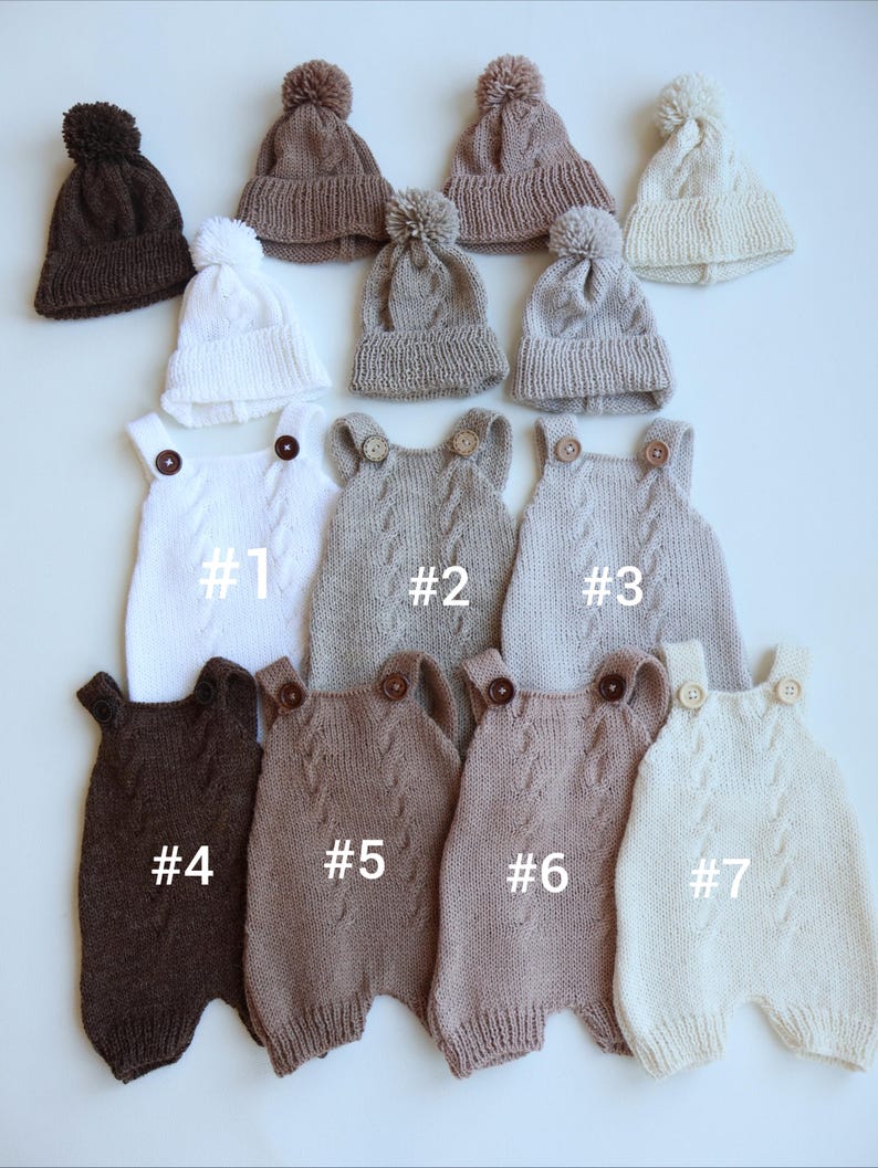 May include: A collection of seven knitted rompers and five matching pom-pom beanies in various neutral shades including white, cream, beige, tan, and dark brown. Each romper features a cable knit pattern, two shoulder buttons, and labels #1-#7.