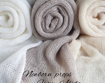 May include: Three rolls of soft, knitted fabric in white, beige, and light brown. The fabric is made of a delicate, airy material and is perfect for newborn photography props. The text "Newborn props from Alida" is written on the fabric.