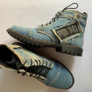 May include: A pair of blue denim boots with black laces and a distressed look. The boots have a black rubber sole and a brown leather accent on the heel.