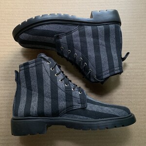 May include: A pair of black and grey striped canvas boots with black laces. The boots have a thick rubber sole.