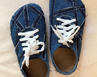 Könnte beinhalten: Ein Paar blaue Jeans-Schuhe mit weißen Schnürsenkeln. Die Schuhe bestehen aus zusammengenähten Jeans-Flicken und haben einen ausgefransten Rand.