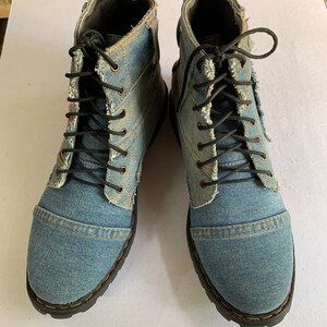 May include: A pair of blue denim ankle boots with black laces. The boots have a distressed look and are made of a soft, comfortable material.