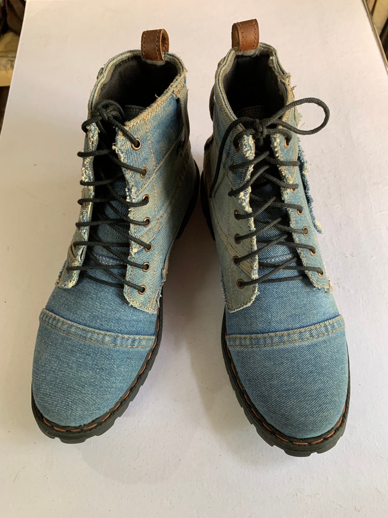 May include: A pair of blue denim ankle boots with black laces. The boots have a distressed look and are made of a soft, comfortable material.