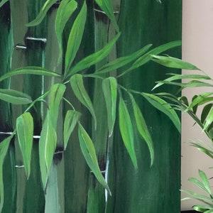 May include: A close-up of a painting depicting a lush green bamboo forest. The painting features multiple stalks of bamboo with green leaves, creating a sense of depth and tranquility.