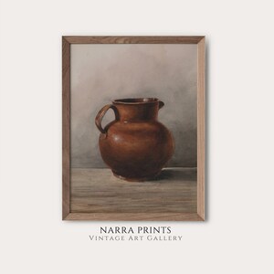 Könnte beinhalten: Ein gerahmtes Aquarellbild eines braunen Keramikkruges auf einem Holztisch. Der Hintergrund ist hellgrau.