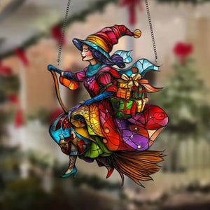 Può includere: Un ornamento in vetro colorato di una strega che vola su una scopa con dei regali. La strega indossa un cappello rosso e un vestito blu. L'ornamento è perfetto per essere appeso a un albero di Natale o a una finestra.