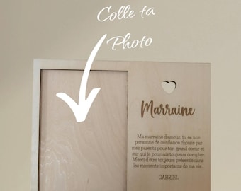 May include: A wooden picture frame with a cutout heart and the word "Marraine" engraved on it. The frame has a space for a photo and the text "Colle ta Photo" above the photo space. The text below the heart reads "Ma marraine d'amour, tu es une personne de confiance choisie par mes parents pour ton grand coeur et sur qui je pourrais toujours compter. Merci d'être toujours présente dans les moments importants de ma vie. GABRIEL."
