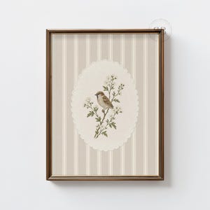 May include: A framed wall art print featuring a brown sparrow perched on a flowering branch. The illustration is centered within a scalloped oval frame against a background of vertical beige and white stripes, all enclosed in a metallic frame.