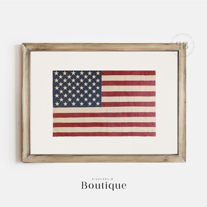 May include: A framed print of a vintage American flag with faded red, white, and blue colors. The flag is displayed in a light wood frame.