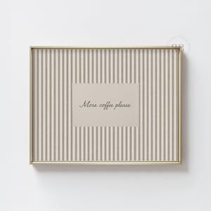 May include: A framed print with a gold-coloured frame. The print has a striped background in beige and grey tones. A beige rectangle in the centre has the text "More coffee please" in a script font.