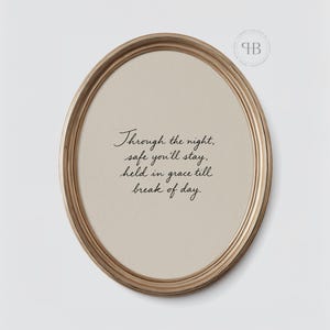 May include: An oval-shaped framed print with a gold-colored frame. The print features the text "Through the night, safe you'll stay, held in grace till break of day" in elegant script on a beige background. A decorative element is in the upper right corner.