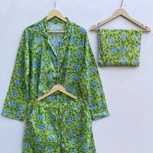 Peut inclure: Ensemble pyjama à imprimé floral vert et bleu avec un haut à boutons et un pantalon assorti. L'ensemble est doté d'un passepoil blanc sur les bords. Le texte "CottonartandCraft" est visible dans le coin inférieur droit de l'image.