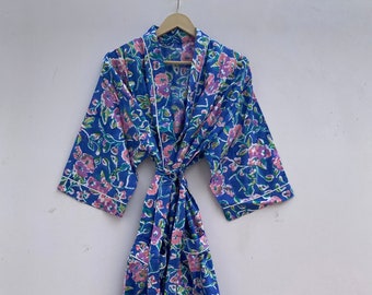 May include: A blue cotton robe with a floral print and white piping. The robe has a tie belt and two pockets. The text "CottonartandCraft" is printed on the bottom of the robe.