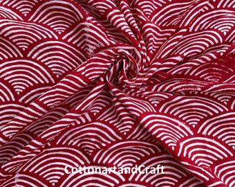 May include: Red fabric with a white wave pattern. The fabric is folded and draped, showcasing the repeating design. The text "cottonartandcraft" is visible on the fabric.