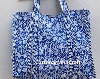 May include: A large blue and white tote bag with a floral pattern. The bag has white stripes on the straps and the words "CottonartandCraft" printed on the front.