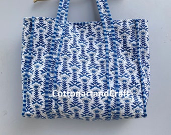 May include: A large white tote bag with blue floral print and blue and white striped trim. The bag has two long straps and the text "CottonartandCraft" is visible on the front.