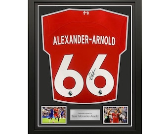 May include: Framed red soccer jersey with the name "ALEXANDER-ARNOLD" and the number "66" in white. Includes two small photos and the text "Personally signed by Trent Alexander-Arnold". The jersey is in a black frame.