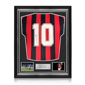 May include: A framed sports jersey featuring red and black vertical stripes with the number 10 in white and a black ink signature. Below the jersey are two small photographs and a silver plaque with the text Personally signed by Ruud Gullit.