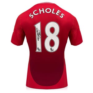 May include: A red short-sleeved sports jersey featuring the name SCHOLES and the number 18 in white lettering on the back. The number 18 includes a black signature on the digit 1 and a small Premier League lion logo at the base of each digit.