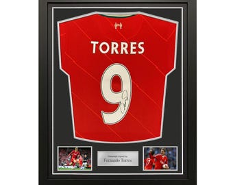 May include: Framed red Liverpool soccer jersey with the name "TORRES" and the number "9" on the back. The jersey is signed by Fernando Torres. The frame includes two smaller photos of Torres playing soccer.