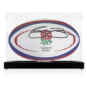 Può includere: Una palla da rugby bianca con strisce rosse e blu, un logo di rosa rossa e il testo "England Rugby". La palla è firmata con inchiostro nero ed è esposta in una teca in acrilico trasparente con una base nera.