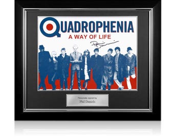 May include: A framed print of the movie poster for Quadrophenia, a 1979 British musical drama film. The poster features a red, white, and blue target logo with the title "Quadrophenia: A Way of Life" and a signature by Phil Daniels.