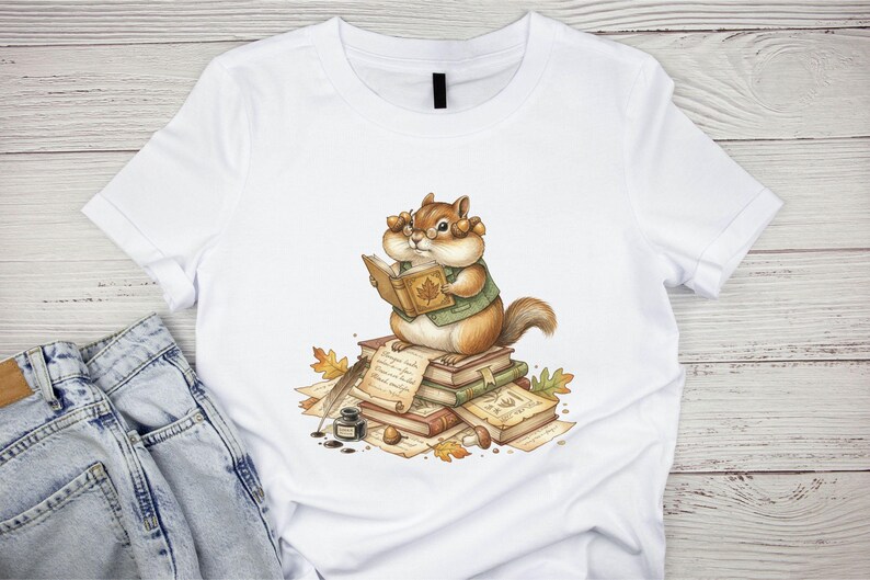 May include: A white t-shirt featuring a graphic of a chipmunk wearing glasses and a green vest, sitting on a stack of books while reading. The illustration includes scattered autumn leaves, a quill pen, an inkwell, and handwritten parchment.