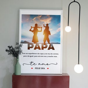 Puede incluir: Una impresi&oacute;n enmarcada en blanco con una silueta de una familia de cuatro personas sobre un fondo de puesta de sol. El texto "PAPA" est&aacute; en letras grandes en la parte inferior de la imagen. El texto "Eres un superh&eacute;roe sin capa y un rey sin corona, pero da igual, para mi eres eso y mucho m&aacute;s. te amo ❤FELIZ D&Iacute;A❤" est&aacute; debajo de la silueta.