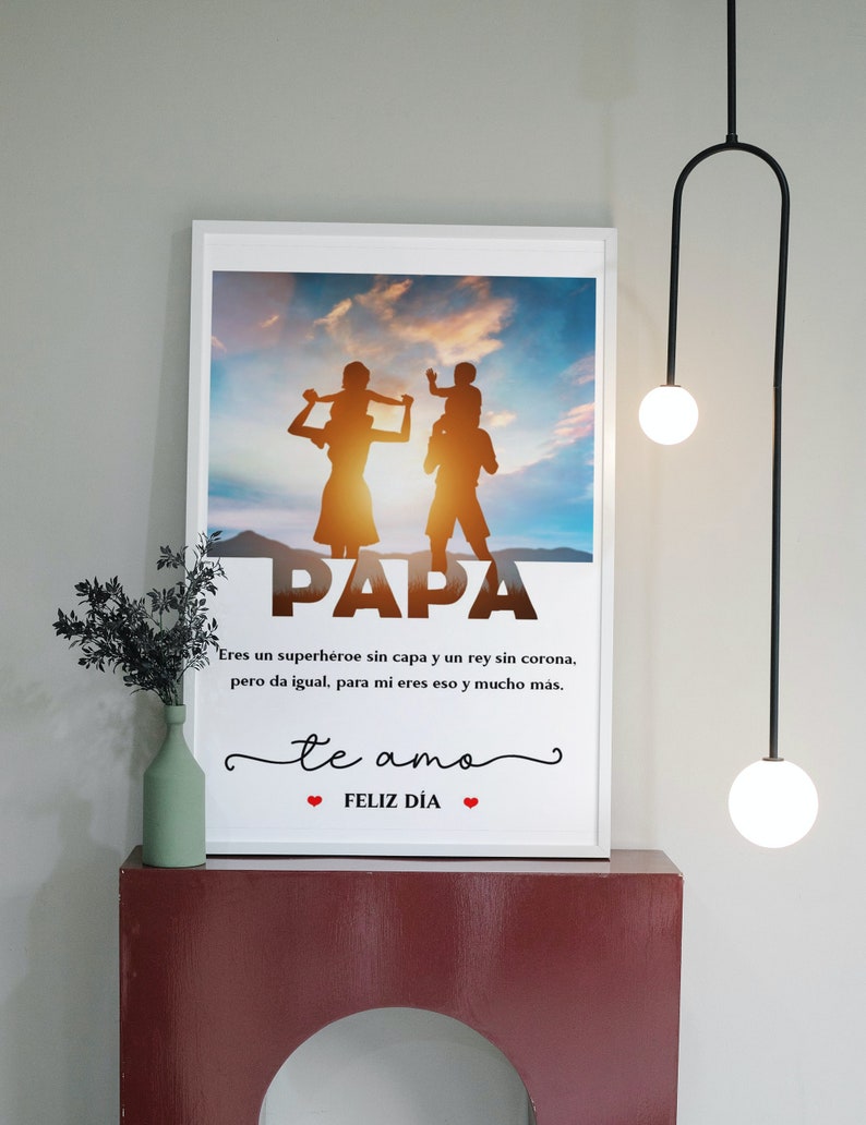 Puede incluir: Una impresi&oacute;n enmarcada en blanco con una silueta de una familia de cuatro personas sobre un fondo de puesta de sol. El texto "PAPA" est&aacute; en letras grandes en la parte inferior de la imagen. El texto "Eres un superh&eacute;roe sin capa y un rey sin corona, pero da igual, para mi eres eso y mucho m&aacute;s. te amo ❤FELIZ D&Iacute;A❤" est&aacute; debajo de la silueta.