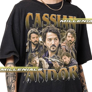 以下が含まれることがあります： スターウォーズシリーズのキャラクター、キャシアン・アンドーのグラフィックが特徴の黒いTシャツ。デザインには、キャラクターの複数の画像と、金色の文字で「CASSIAN」と「ANDOR」の文字が含まれています。「MILLENIALS」という言葉もシャツにプリントされています。
