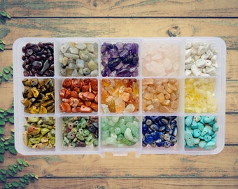 May include: A clear plastic storage box with 12 compartments filled with various colored gemstone chips. The chips are arranged in rows of different colors, including red, orange, yellow, green, blue, purple, and white.