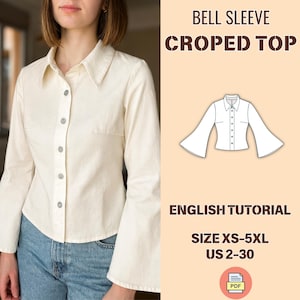 以下が含まれることがあります： クリーム色のベルスリーブクロップドトップ、ボタンダウンフロント。画像には「BELL SLEEVE CROPPED TOP」と「ENGLISH TUTORIAL」の文字が含まれています。サイズはXS-5XL、USサイズ2-30です。PDFアイコンも表示されています。