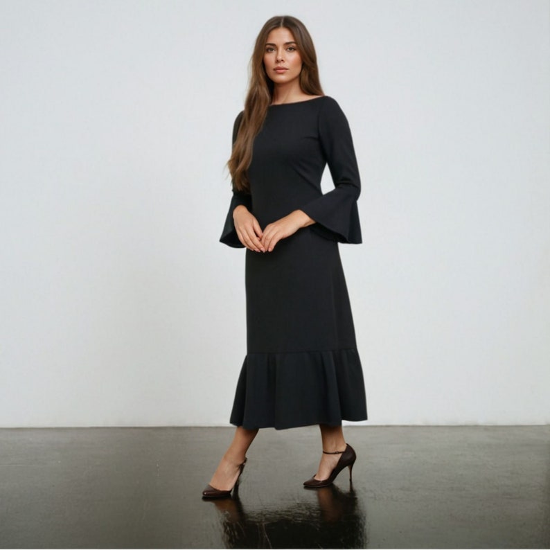 May include: A black midi dress with long sleeves and a ruffled hem. The dress has a boat neckline and a fitted silhouette.