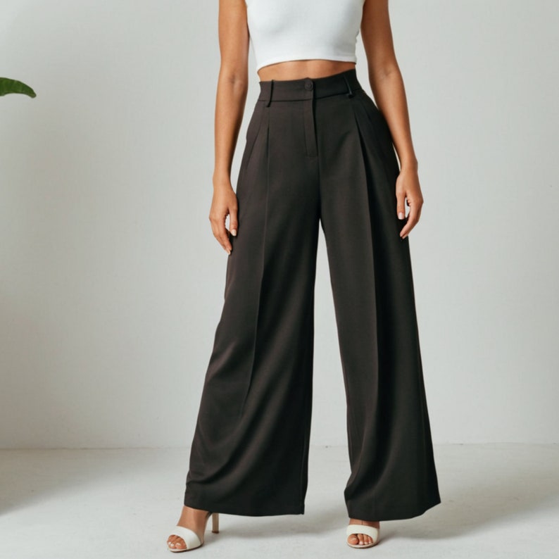 Op de afbeelding: Een wijde, donkerbruine broek met een hoge taille en plooien. De broek is gemaakt van een gladde, zijdeachtige stof.
