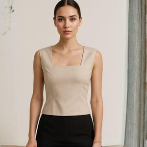 Peut inclure: Un haut sans manches beige avec un col carr&eacute;, associ&eacute; &agrave; un pantalon noir. Le haut a une coupe ajust&eacute;e et un d&eacute;tail de couture &agrave; la taille. Le style est minimaliste et professionnel, id&eacute;al pour le travail.