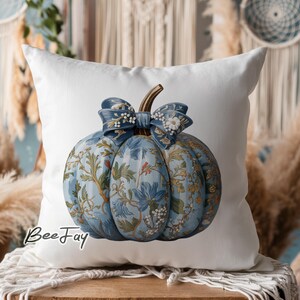 May include: A white pillow with a blue and white floral patterned pumpkin with a blue bow. The pillow has the text "Bee Jay" printed on it.