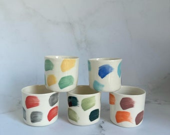 May include: Set of six ceramic mugs with abstract brushstroke designs in various colors, including yellow, green, blue, red, gray, and orange.