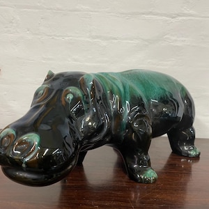 Könnte beinhalten: Eine Keramikfigur eines Flusspferdes mit schwarzer und grüner Glasur. Das Flusspferd steht auf allen vieren und hat eine lange Schnauze.